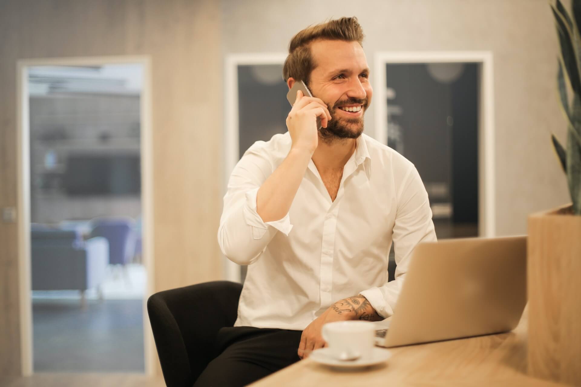 a person sitting at a table with a laptop and phone